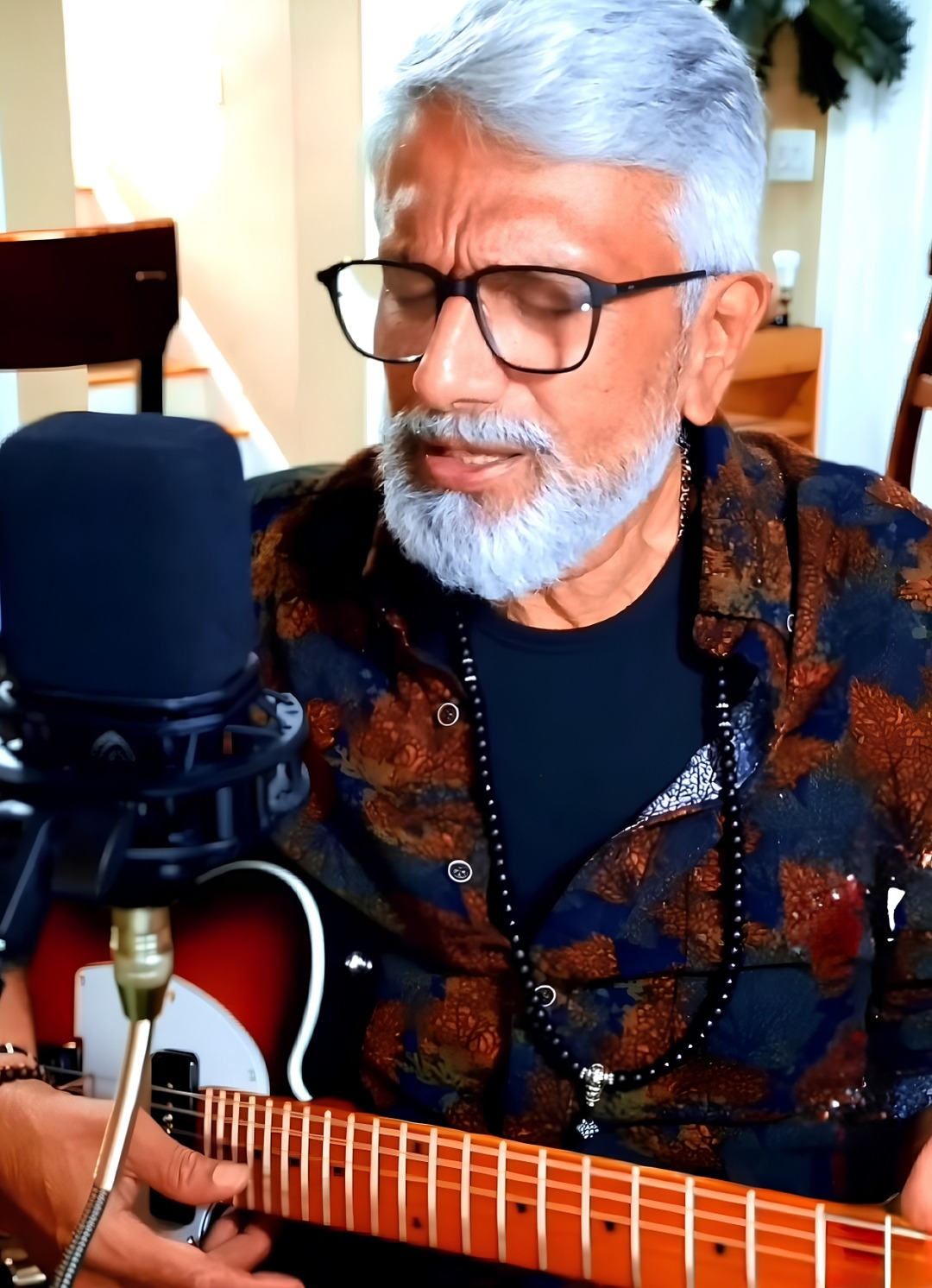 Nandakumar Nayar singing with his guitar at the microphone